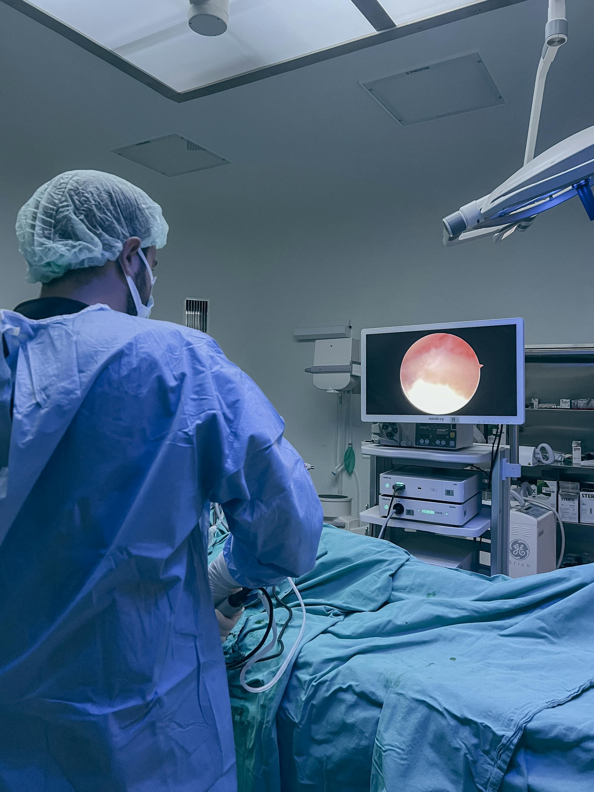 Surgeon in protective clothing performing endoscopic surgery in a hospital operating room.